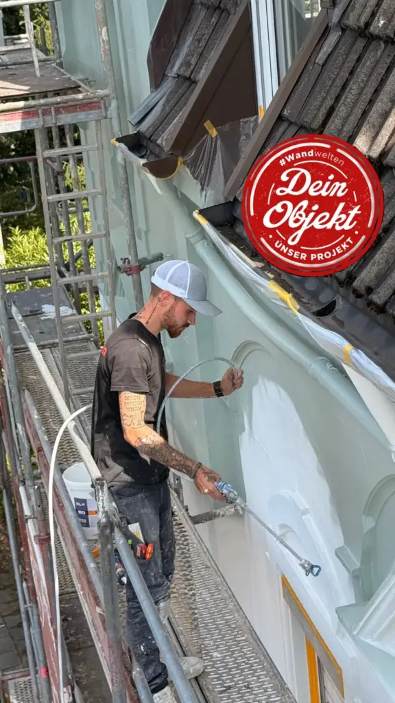 Maler beschichtet die Altbau-Fassade mit dem Airless-Spritzgerät