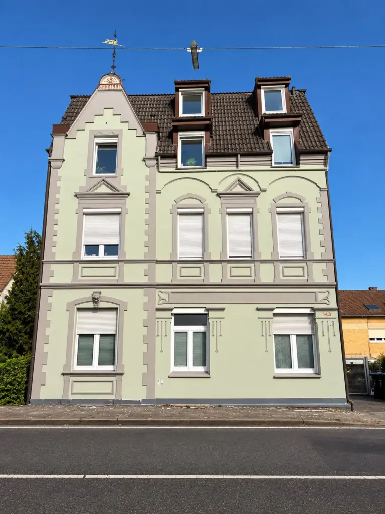 Fertige Altbau-Fassade in Hellgrün mit grau abgesetzten Fensterfaschen und Stuckelementen
