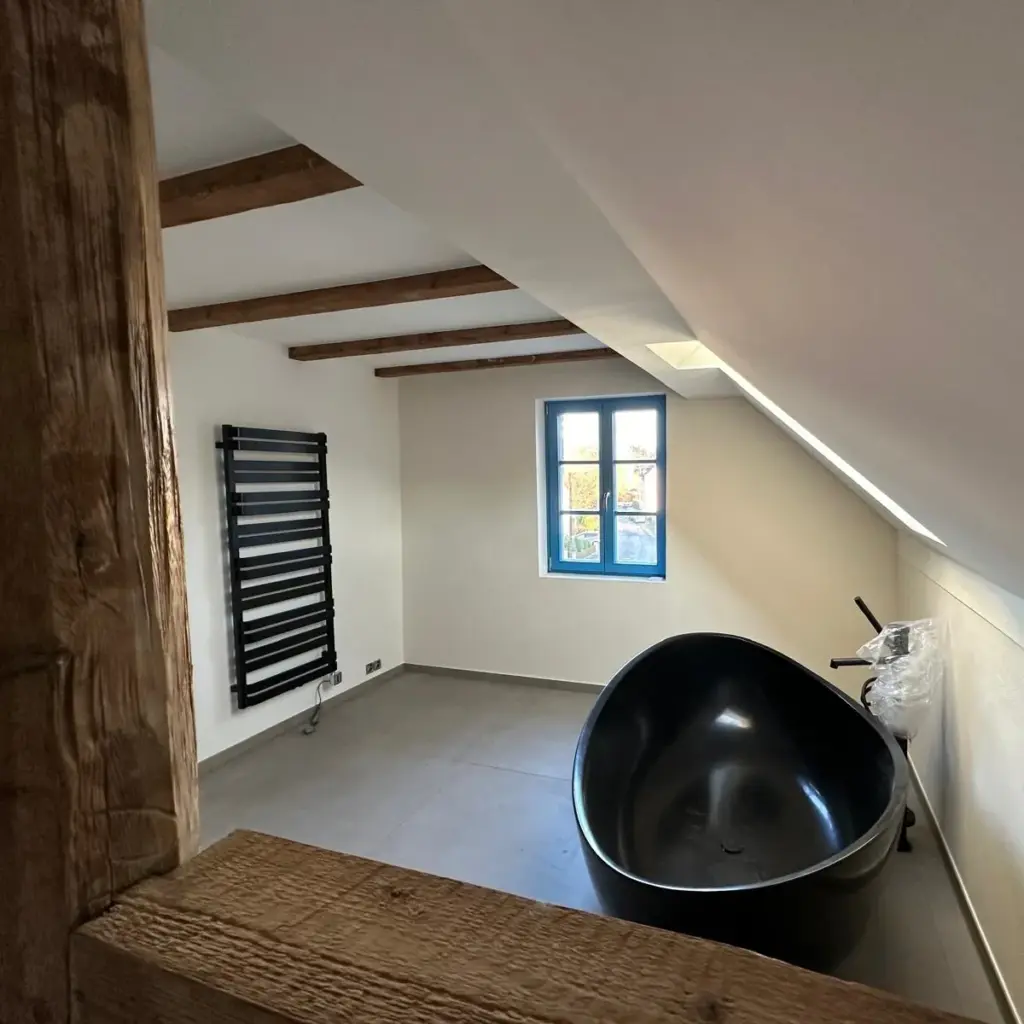 Bad im Dachgeschoss mit schwarzer freistehender Badewanne und Holzbalken