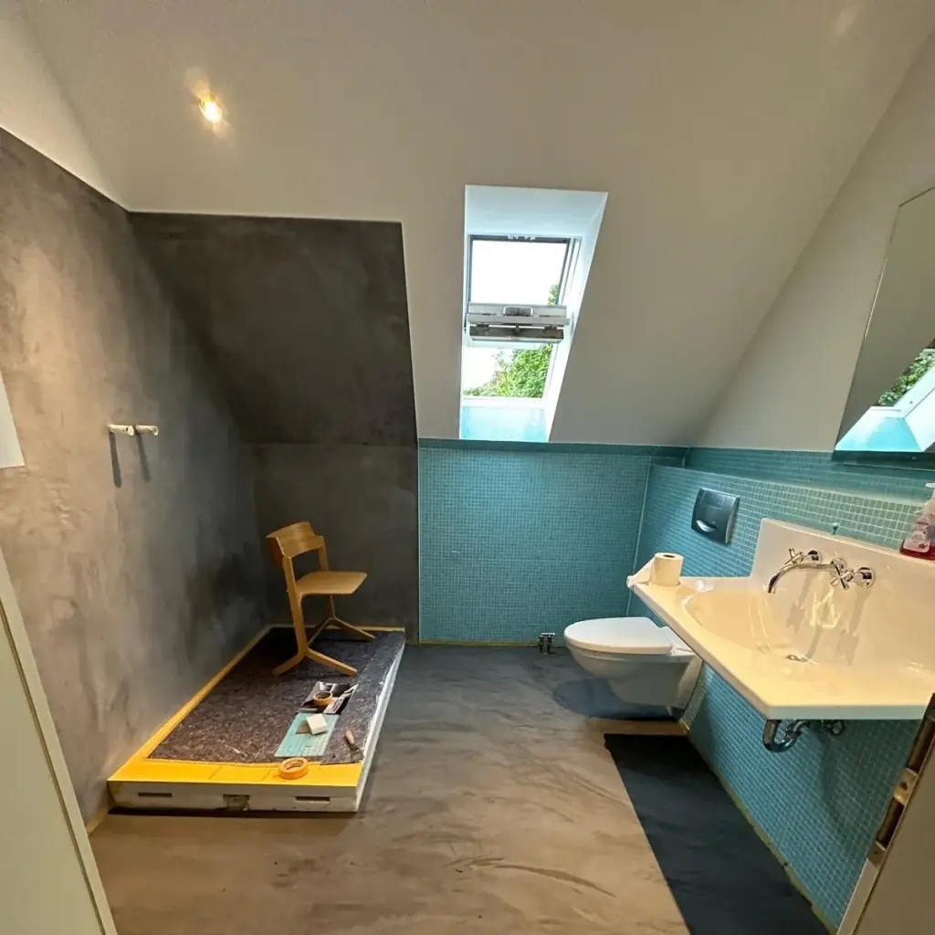 Bad unter der Dachschräge mit Mosaik und Wand in Betonoptik