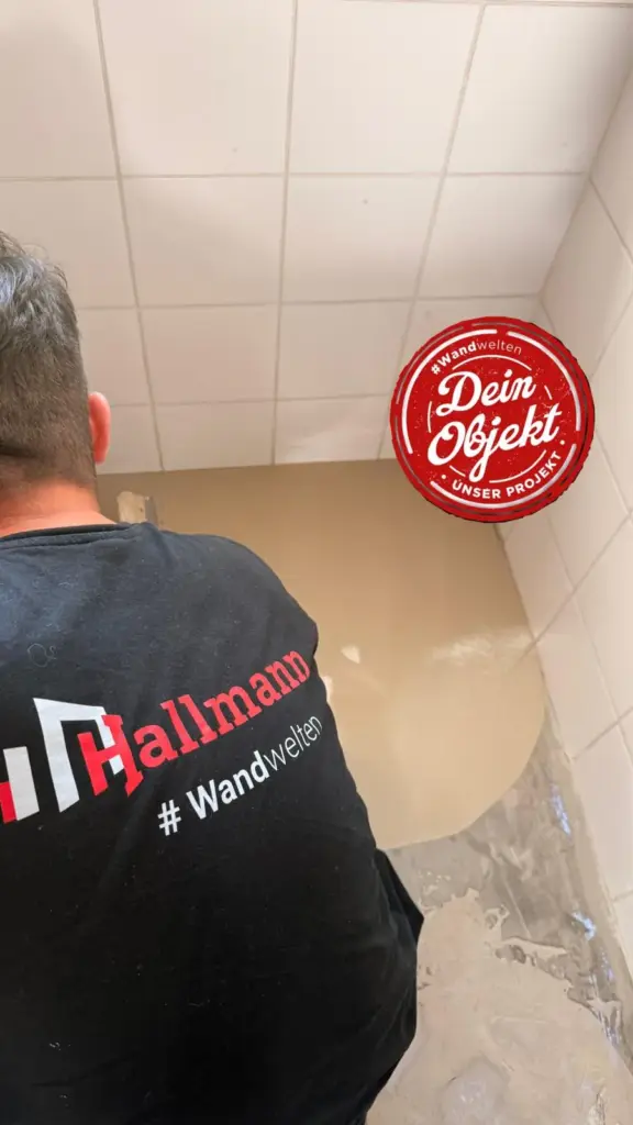 Mitarbeiter von Wandwelten trägt die Bodenbeschichtung im Badezimmer auf