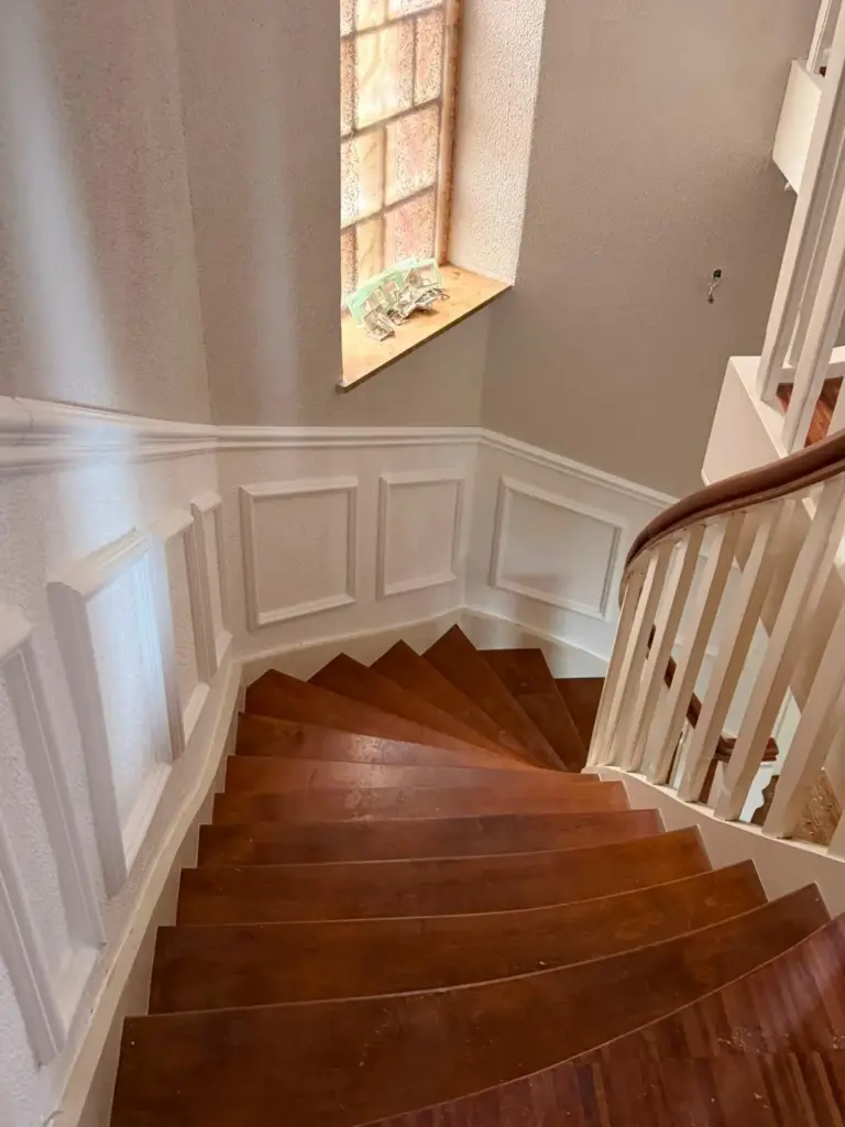 Treppenhaus mit Holztreppe und weißer Wandvertäfelung