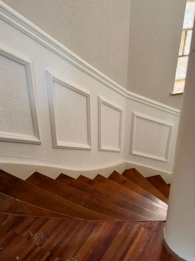 Weiße Kassetten-Wandvertäfelung entlang der Treppe
